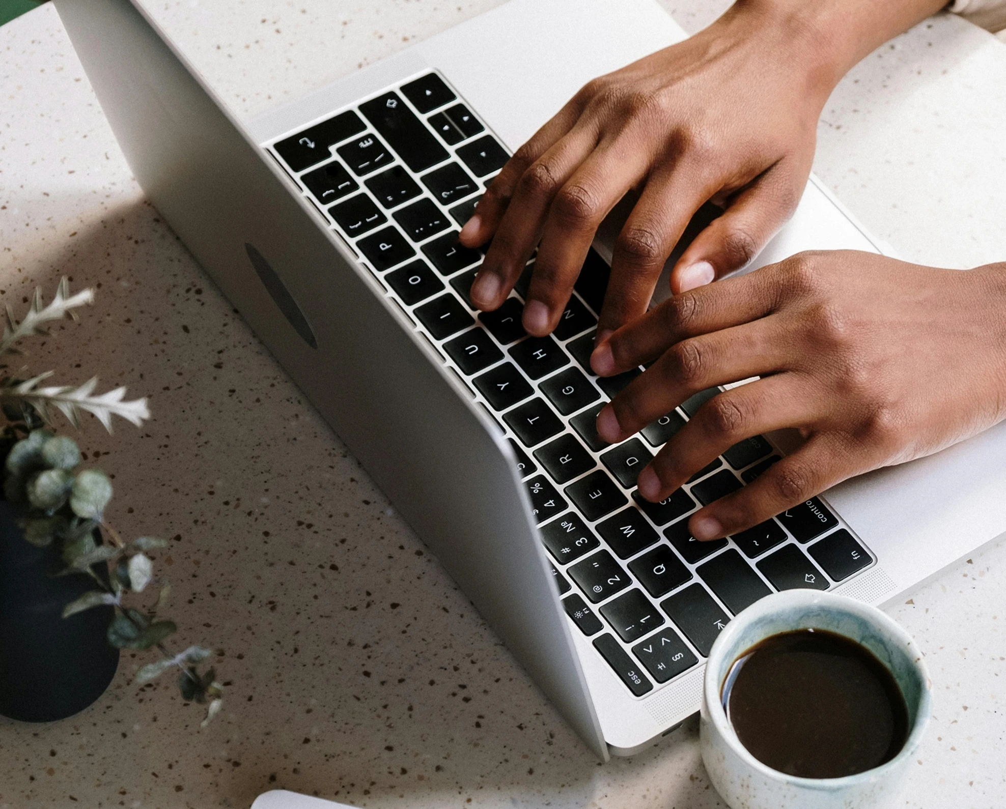 Person working on a laptop with coffee and tablet